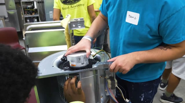 Students learning electrical assembly in workshop.